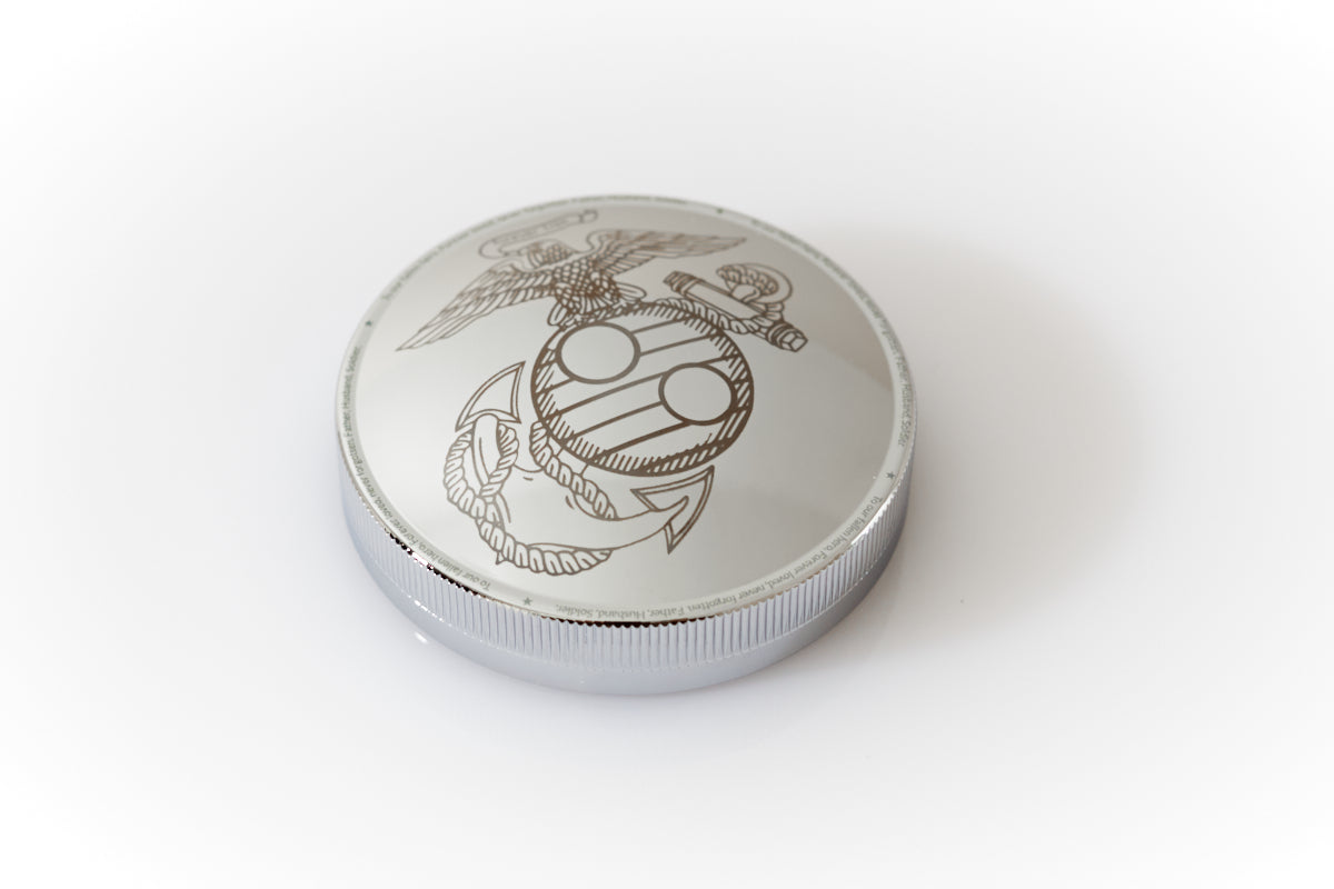 Close-up of a polished chrome screw-top lid from the Haus of Urns Freedom Urn, featuring a detailed laser engraving of a custom emblem inspired by the United States Marine Corps Eagle Globe and Anchor. A personalised memorial inscription is engraved around the outer rim of the lid, adding a deeply personal tribute to this handcrafted military cremation urn.