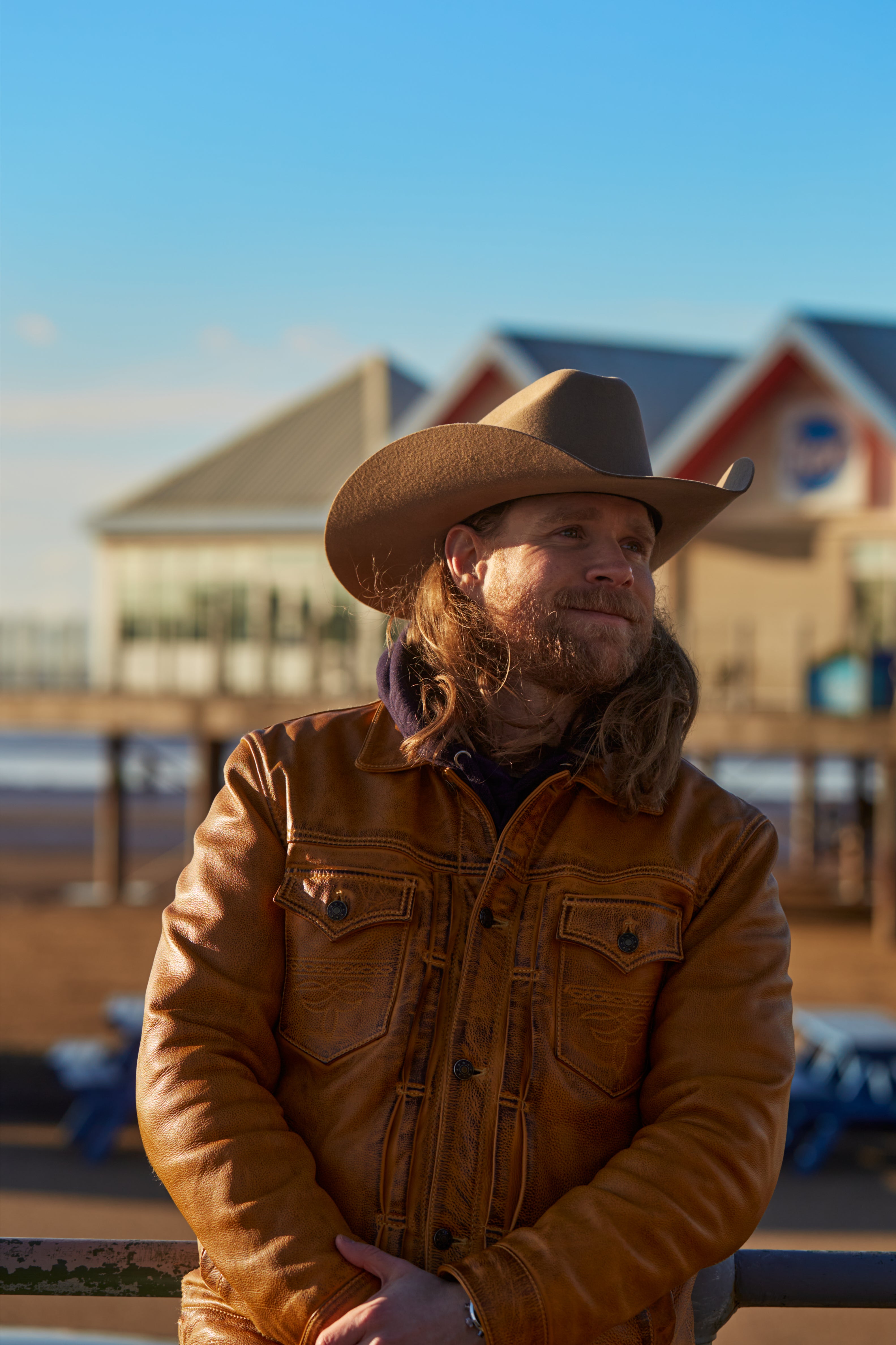 Mario Venier, founder of Haus of Urns, handcrafted memorial urns, standing outdoors in a leather jacket and cowboy hat